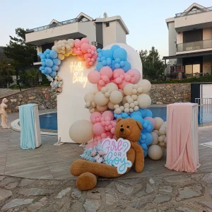 Poolside birthday setup with pastel balloons and teddy bear