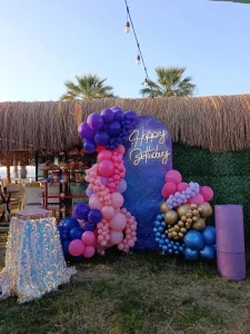 Garden birthday party with pink and purple balloons and Happy Birthday sign