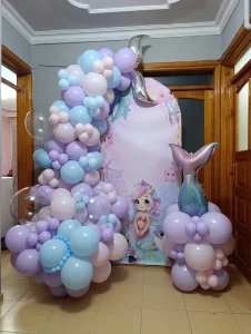 Pink and lilac balloon backdrop with character figures at a birthday party