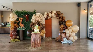 Indoor birthday setup with brown and cream balloon arches
