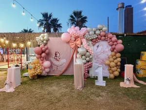 Colourful balloon garland around a palm tree at an outdoor birthday party