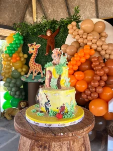 Orange themed cake table with teddy bear and balloons for a kids birthday