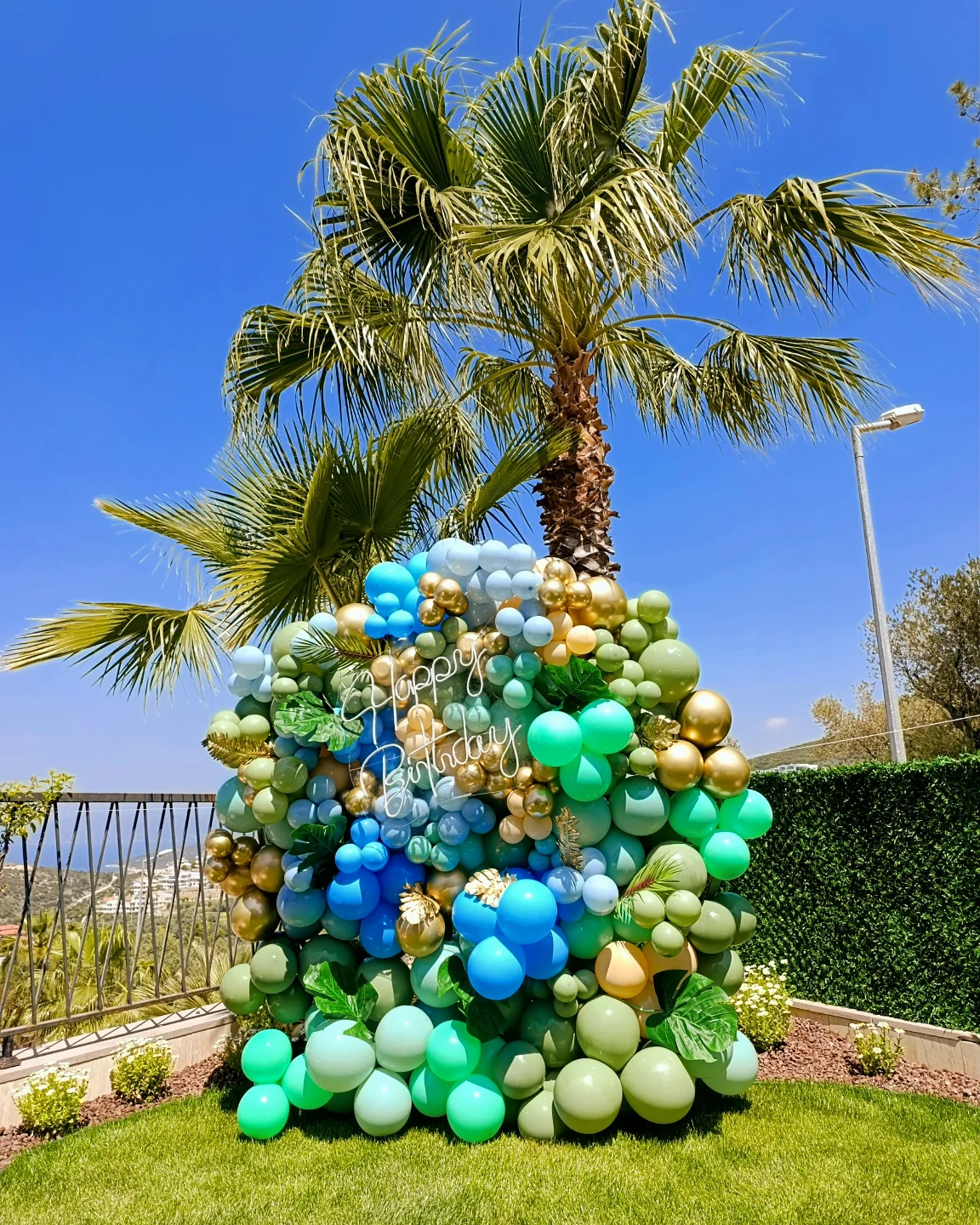 Blue and green balloon sphere in a garden with palm trees
