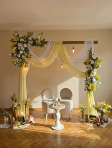 Engagement backdrop with yellow drapes and flower arch