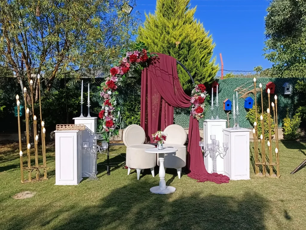 Engagement party in Kusadasi garden with burgundy draped floral arch and gold stands