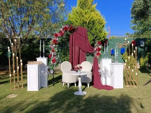 Engagement party in Kusadasi garden with burgundy draped floral arch and gold stands