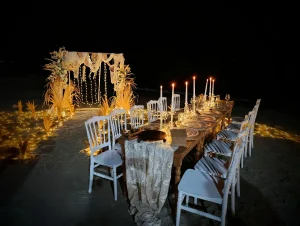 Night beach dinner table with candles and pampas arch