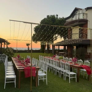 Seaside garden event with long tables and string lights at sunset