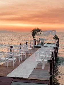 Sunset beach wedding setup with white chairs on a pier in Kusadasi
