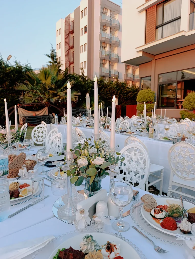 Long outdoor wedding dinner table with tall candles and flowers in Kusadasi