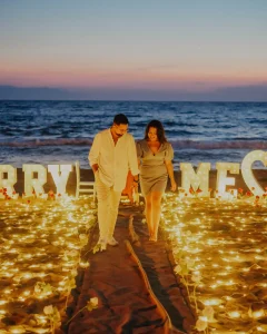 Couple on the beach in front of Marry Me letters at sunset in Kusadasi