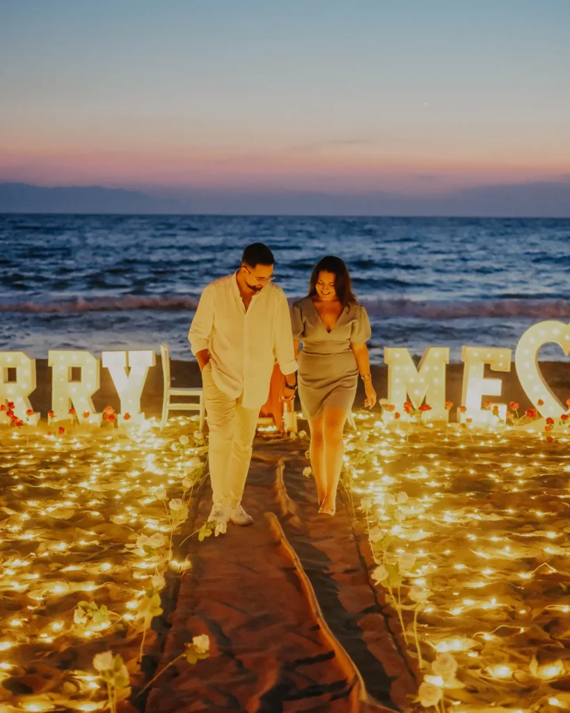 Couple on the beach in front of Marry Me letters at sunset in Kusadasi